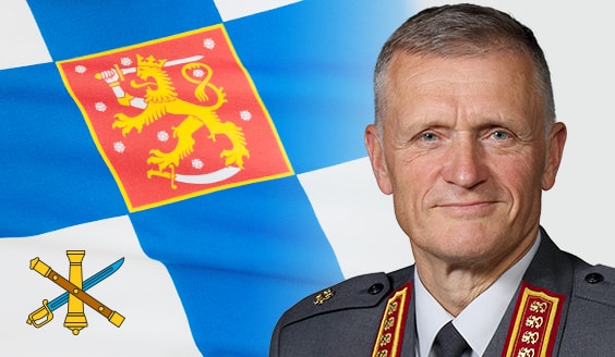Kuvassa Puolustusvoimain komentaja, kenraali Timo Kivinen. Hänellä on yllään harmaa sotilasasu, jossa on molemmissa kauluslaatoissa neljä leijonaruusuketta. Taustalla on Puolustusvoimain komentajan lippu.