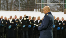 Sotilas puhuu mikrofoniin, taustalla näkyy sotilaita muodossa lakit kädessä