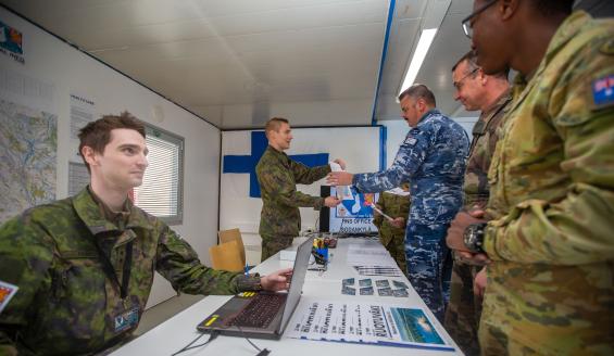 Two Finnish soldiers on one side of the table and three foreigners on the other side