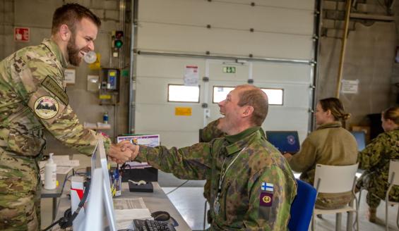 Suomalainen ja ulkomaalainen sotilas kättelevät ja nauravat