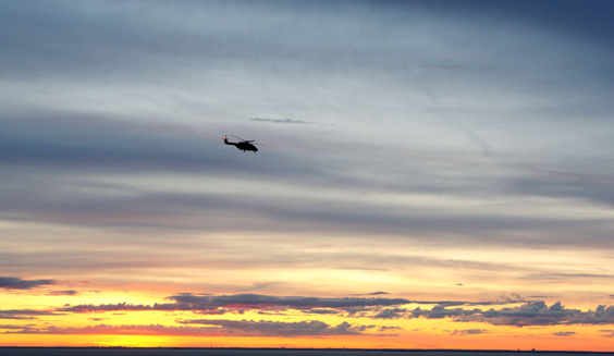 The Defence Forces take the environment into account in everything they do. The Finnish Defence Forces' helicopter flying over the sea at sunset. Photo the Finnish Defence Forces, Lisa Hentunen.