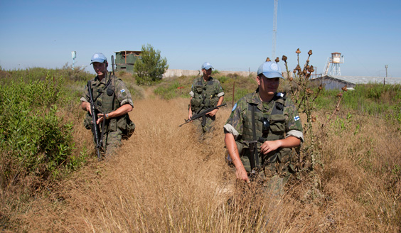 Three Finnish soldiers in blue hats on a haystack