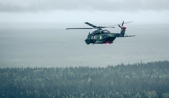 Helikopteri ilmassa metsän yläpuolella.