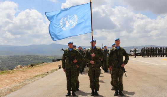 Sotilaat marssivat muodossa UN-lipun perässä