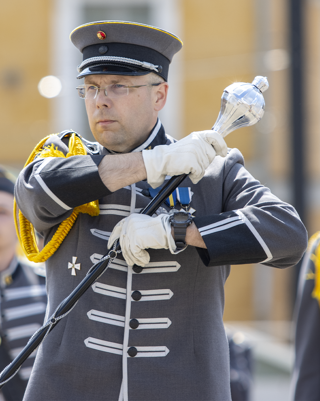 Riku Penttilä johtamassa soittokunnan marssia marssikapellimestarin sauva kädessään.