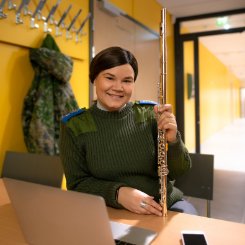 Annilla on kädessä huilu ja edessä kannettava tietokone.