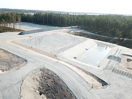 - the open, wide area of Syndalen’s new explosion site which consists of an explosion field, water treatment pool and a protection berm made out of crushed stone. Forest in the background.