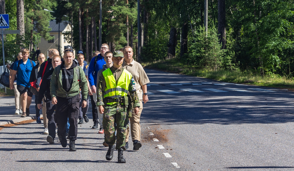 Uusia alokkaita ryhmässä, kävelemässä varuskunta-alueella sotilaspoliisin perässä.