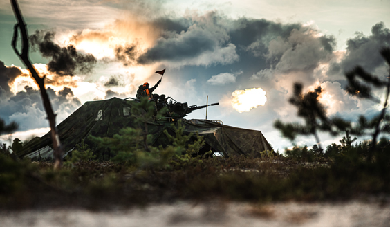 Varusmiehet ampuvat ilmatorjukanuunalla (23ITK61), joka on naamioidun ajoneuvon lavalla. Taustalla pilviä, joiden välistä pilkistää aurinko.