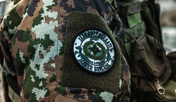 Maastokuvioisen talvitakin hihassa näkyy merkki, jossa lukee Jääkäriprikaati, Jaeger brigade, pohjoisen puolustajat.