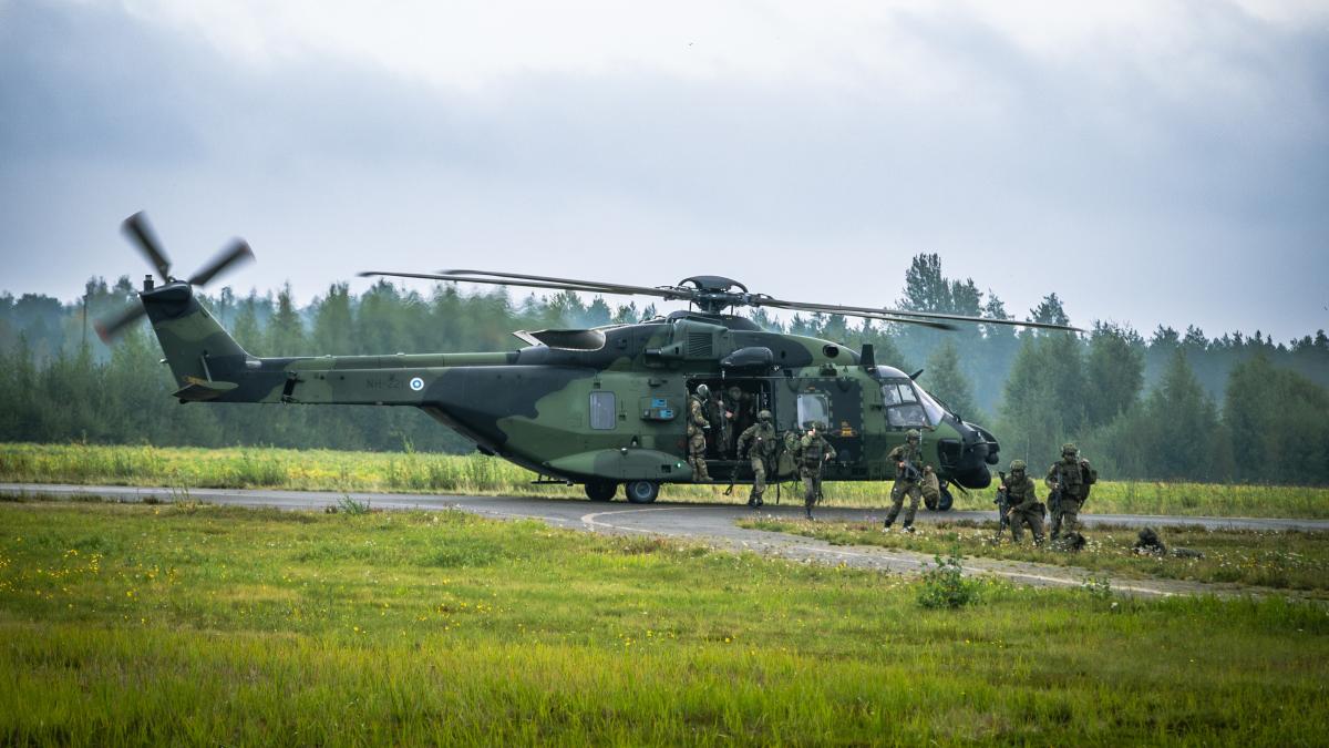 Helikopteri on laskeutunut maahan ja varusmiehet jalkautuvat maastoon.