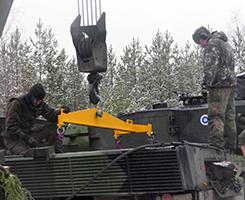 Miehiä panssarivaunun päällä, taustalla lumista havumetsää.