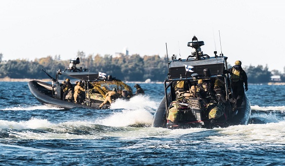 Kaksi Puolustusvoimien mustaa venettä kulkee merellä saariston edustalla. Veneiden kyydissä on taisteluvarustuksessa olevia sotilaita.