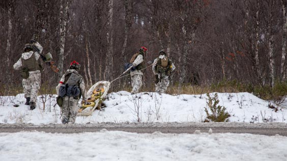 Soldiers pulling a sled and moving forward in a snowy forest