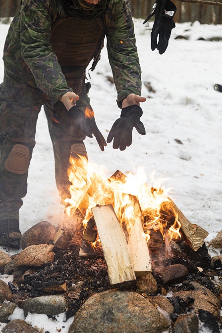 Aliupseeri kuivattelee käsineitään nuotiolla.