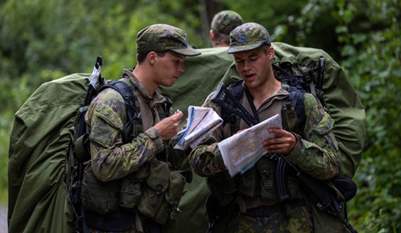 Urheilukoulun varusmiehiä metsässä tiedusteluharjoituksessa lukemassa karttaa.