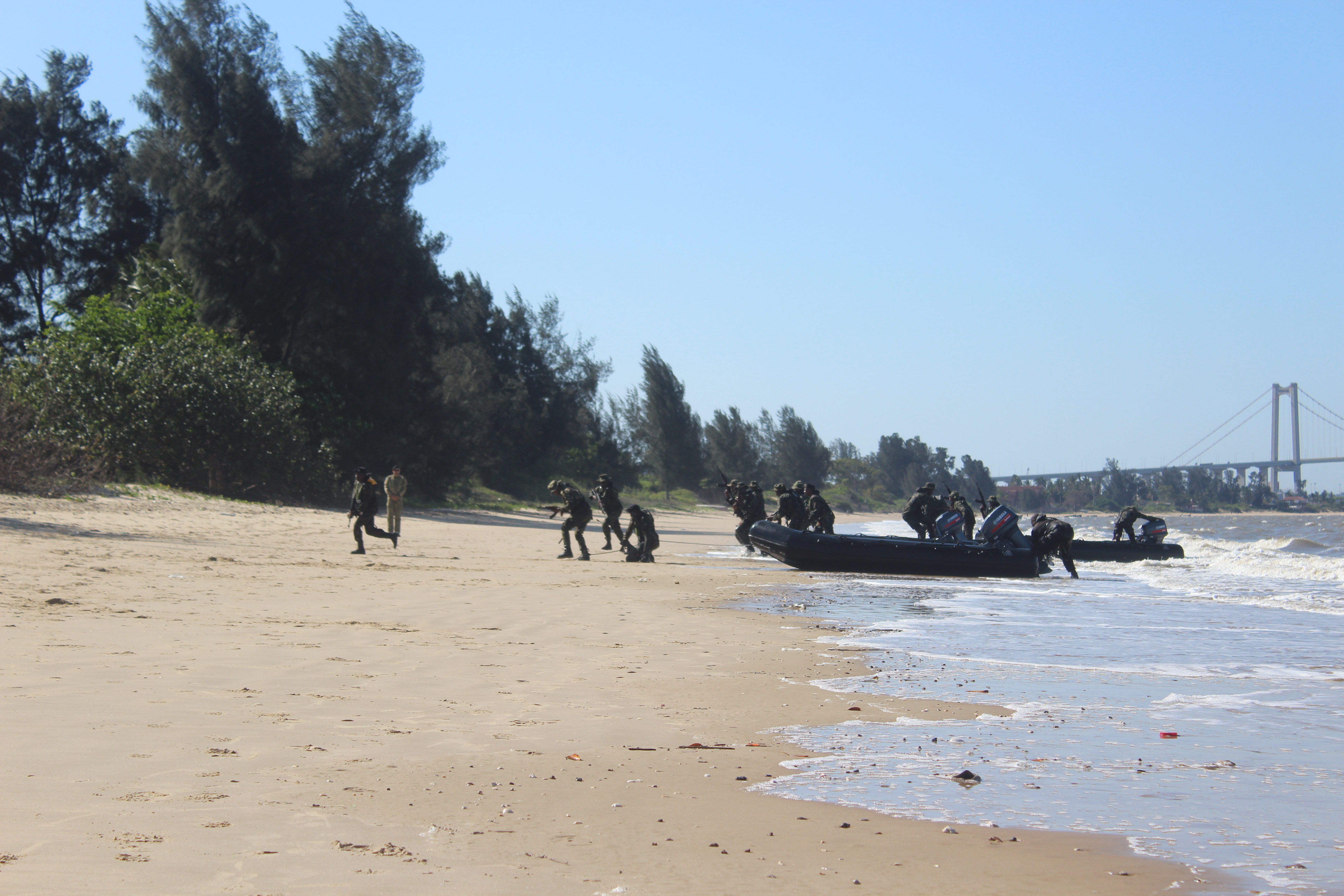 Henkilöitä EUMAM MOZ -operaatiossa rannalla veneen kanssa.