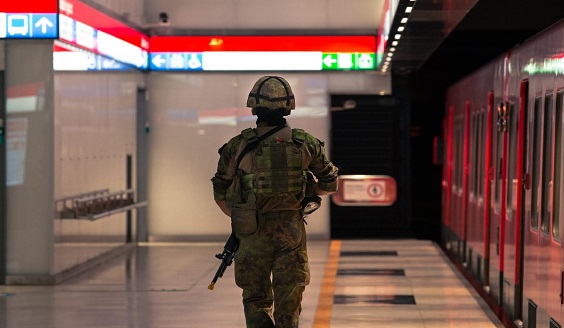 taisteluvarustuksessa oleva sotilas kävelee metrotunnelissa selkä kameraan päin