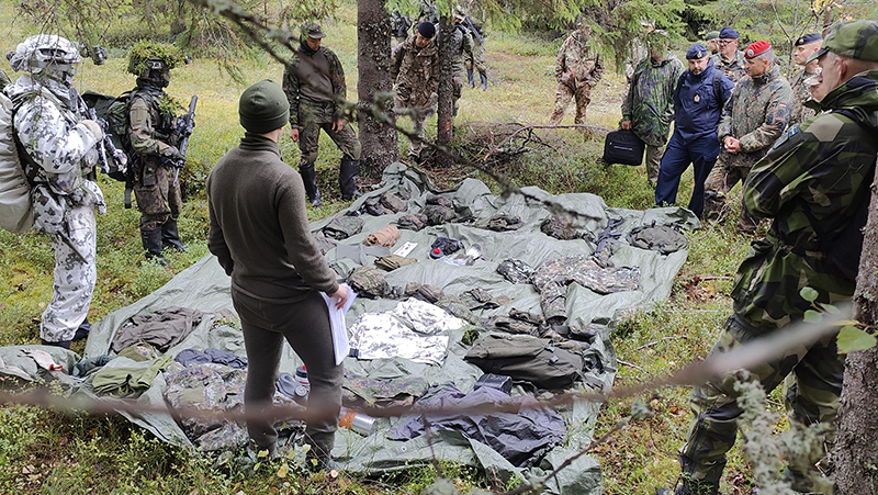 Sotilaita metsässä seuraamassa varusteiden esittelyä.