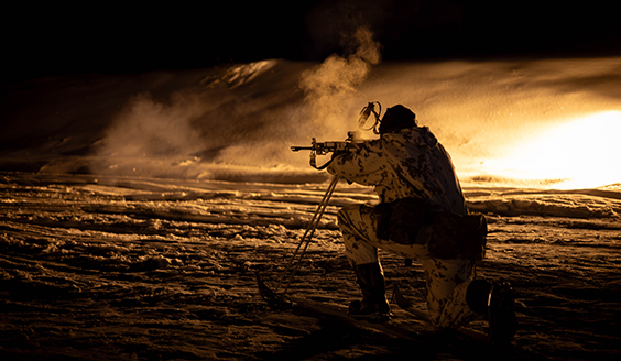 Sotilas ampumassa pimeässä sukset jalassa.