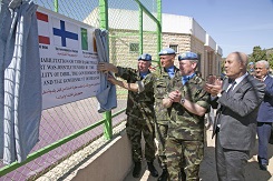 Three soldiers reveal a sign with flags and text from different countries behind the curtain. Civilians clapping.