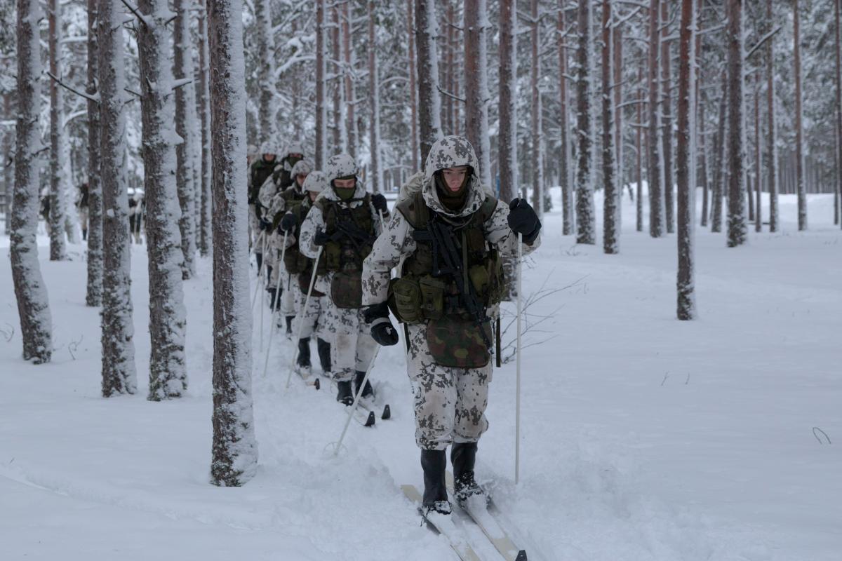 Joukko alokkaita hiihtomarssilla lumisessa metsässä