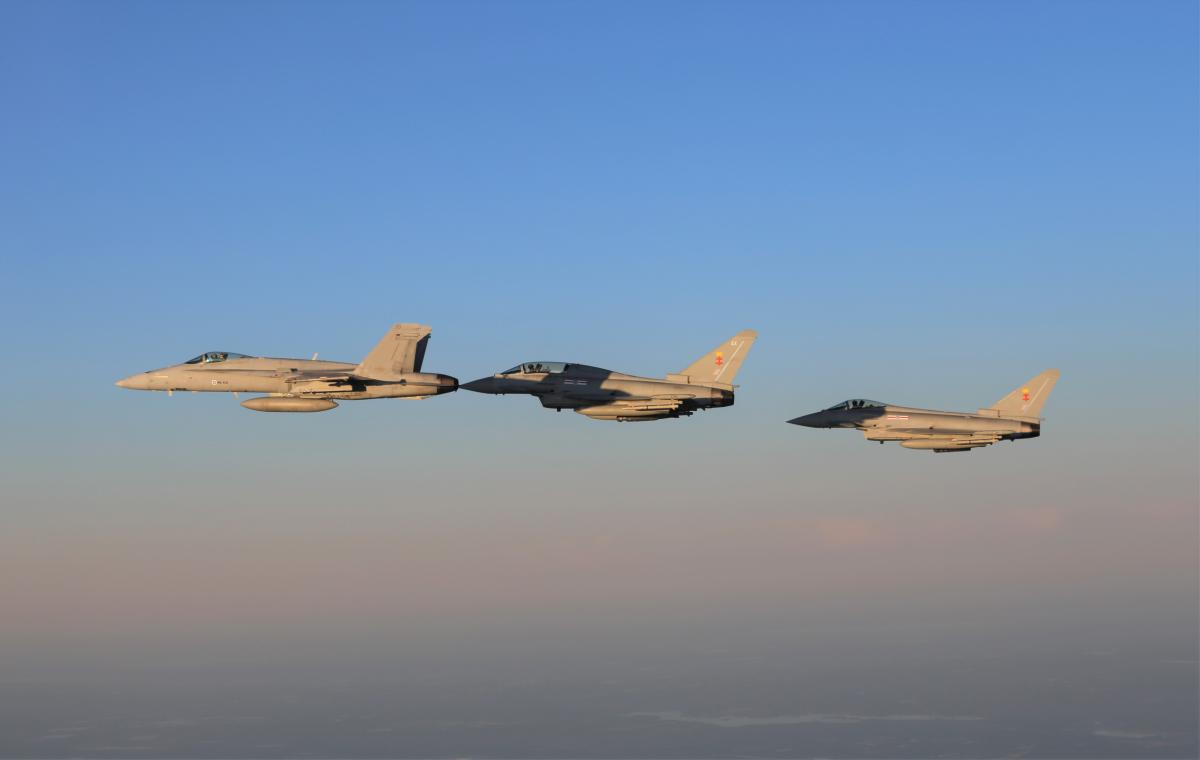 Suomen ilmavoimien F/A-18 Hornet ja kaksi Ison-Britannian kuninkaallisten ilmavoimien Eurofighter Typhoon -hävittäjää auringonlaskussa taivaalla.