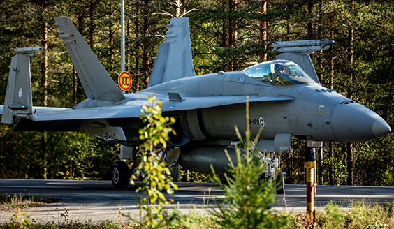 Hornet-hävittäjä rullaa asfaltilla, taustalla metsää.