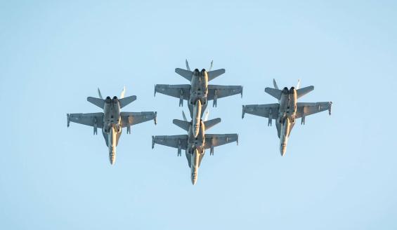 Neljä Suomen Ilmavoimien F/A-18 Hornet -monitoimihävittäjää lentää taivaalla tiiviissä timanttimuodostelmassa.