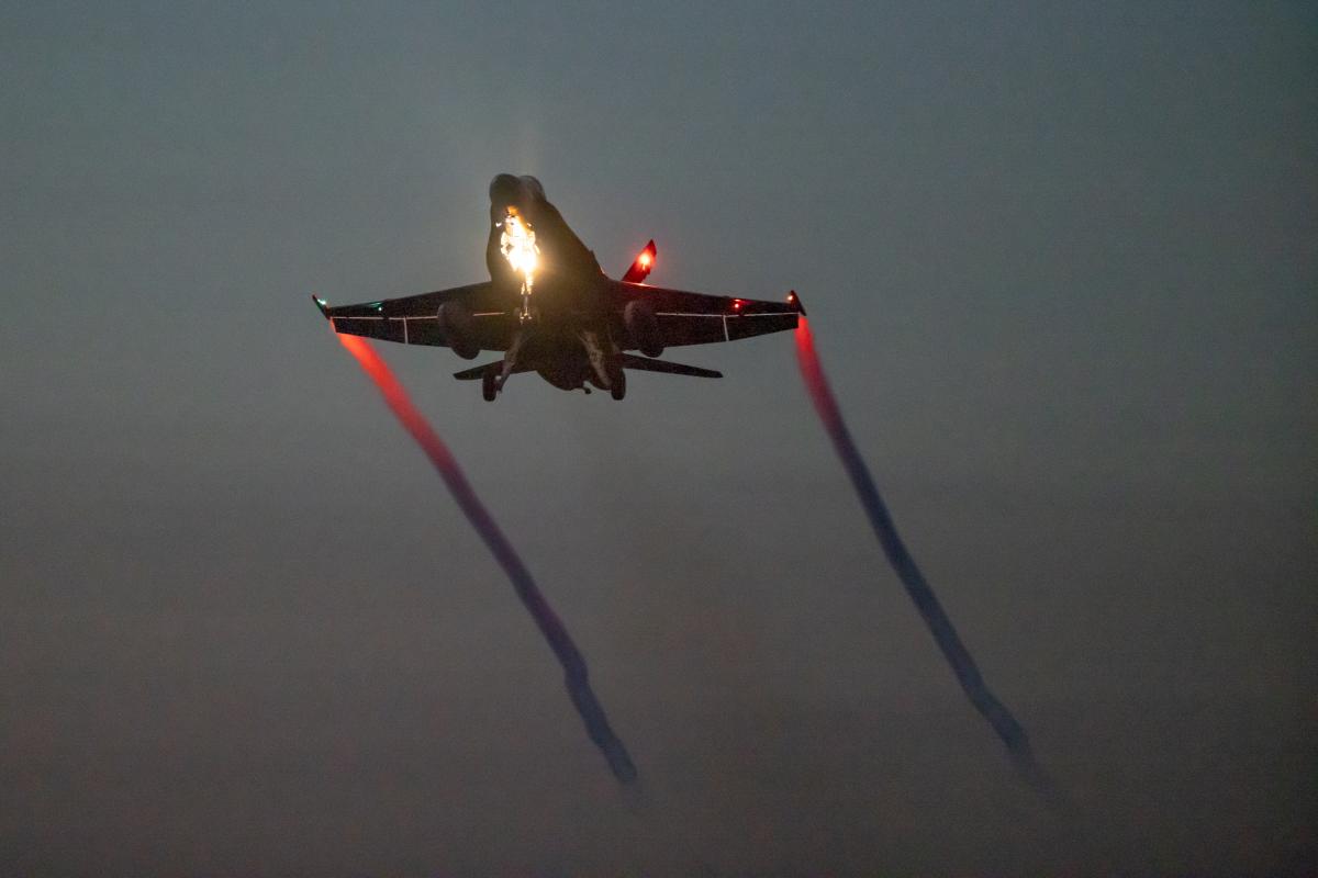 Hornet-hävittäjä nousee ilmaan pimeällä.