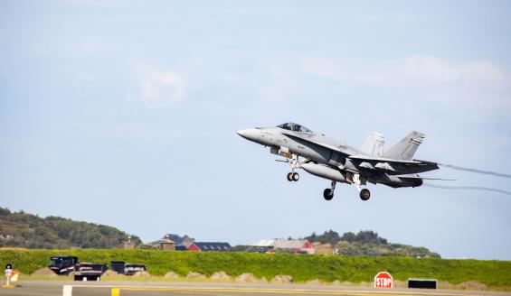 Maasta otetussa kuvassa Suomen ilmavoimien Hornet-hävittäjä nousemassa ilmaan kiitotieltä taustallaan kesäistä norjalaista maalaismaisemaa.