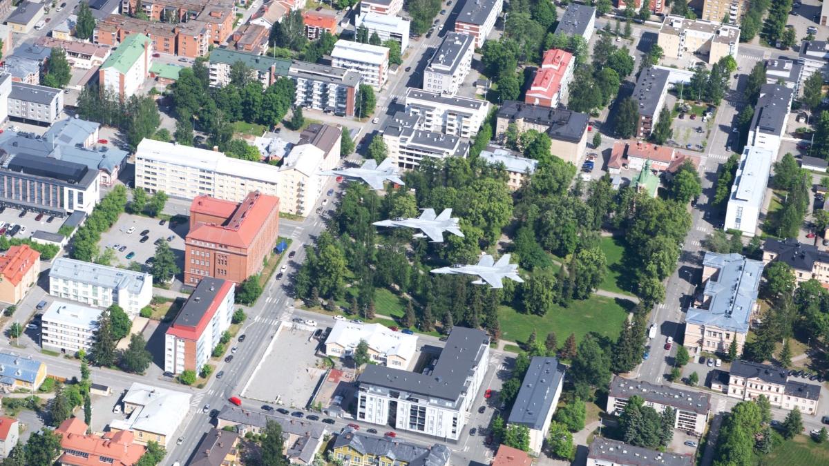 Kolme Ilmavoimien Hornet-hävittäjää lentää rivimuodostelmassa Kuopion kaupungin yllä.