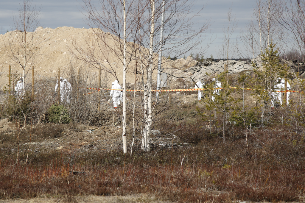 Valkoisiin suojahaalareihin pukeutuneita ihmisiä onnettomuusalueella.