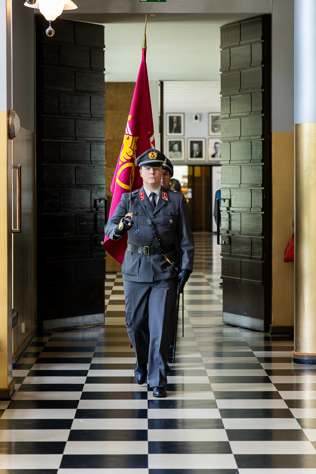 Maanpuolustuskorkeakoulun lippu saapuu Maanpuolustuskorkeakoulun juhlasaliin. Sotilaat kantavat lippua.