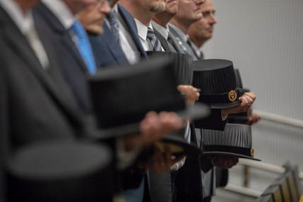 Miehet seisovat rivissä silinterihatut kädessä.