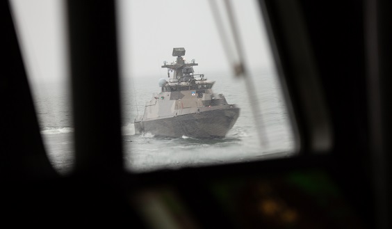 A view out from a ships window to the snowstormy sea where there is a missile boat.