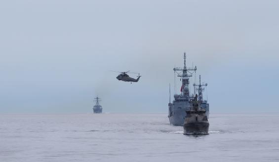 Helikopteri ja sota-aluksia liikkumassa merialueella.
