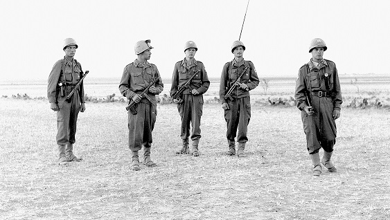 Black and wgite picture. Patrol of five men with guns returning to the base