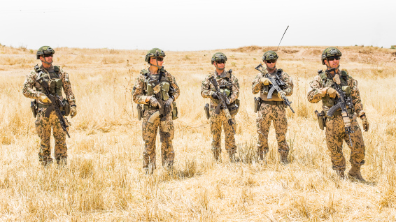 Patrol of five men with full gear on the field.