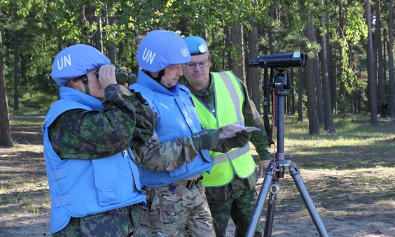 Two soldiers with UN blue helmets and their instructor standing and observing
