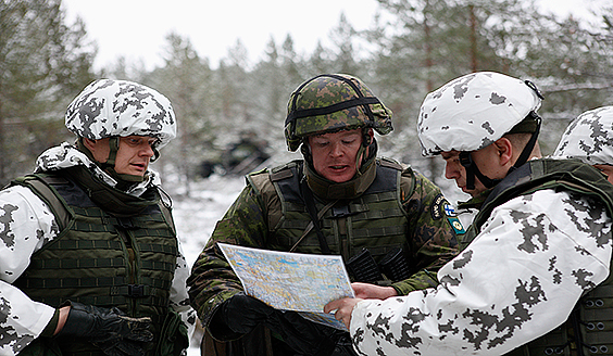  Kolme sotilasta tutkii karttaa lumisessa metsässä