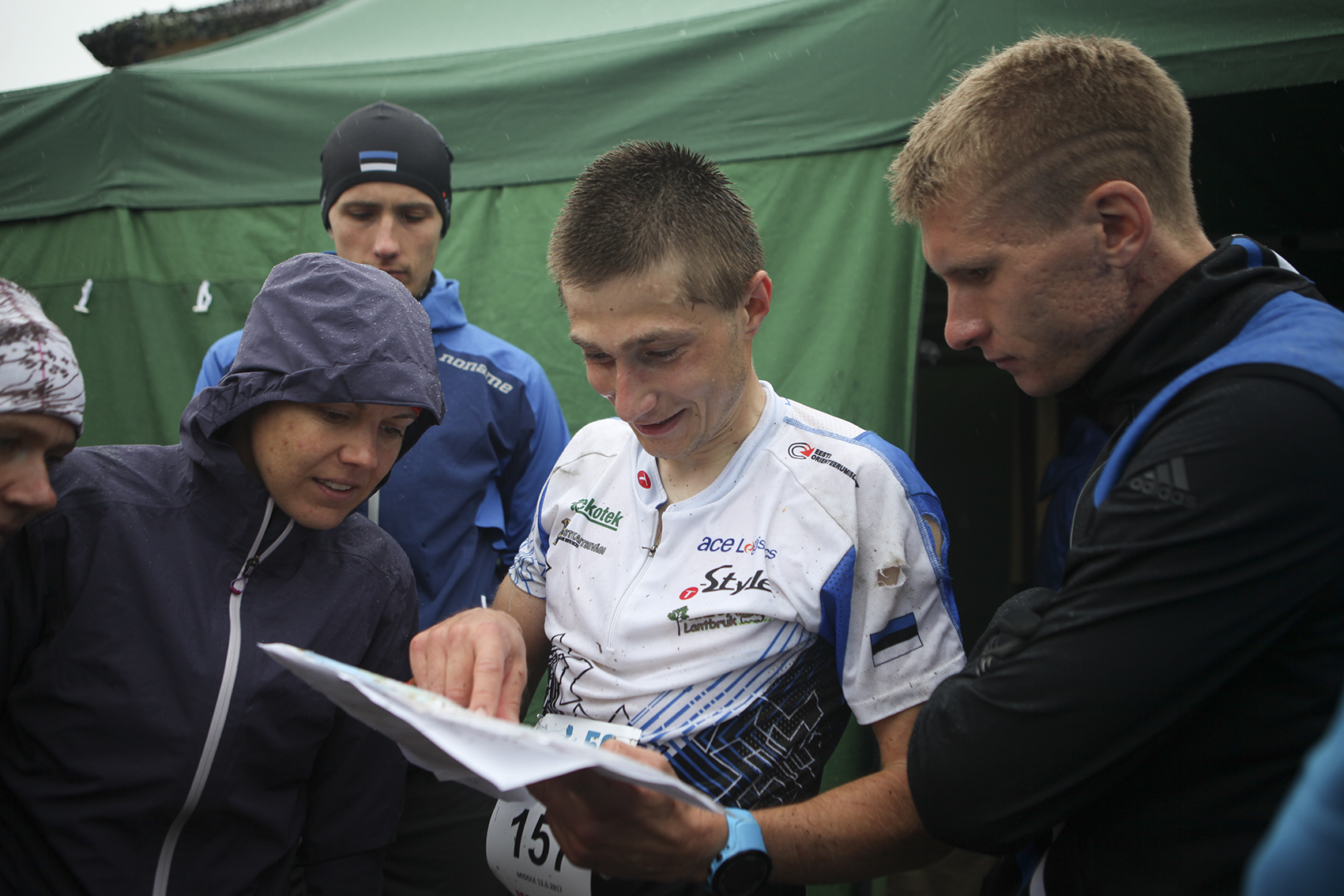 A man in sports clothes is showing something on a paper to other people