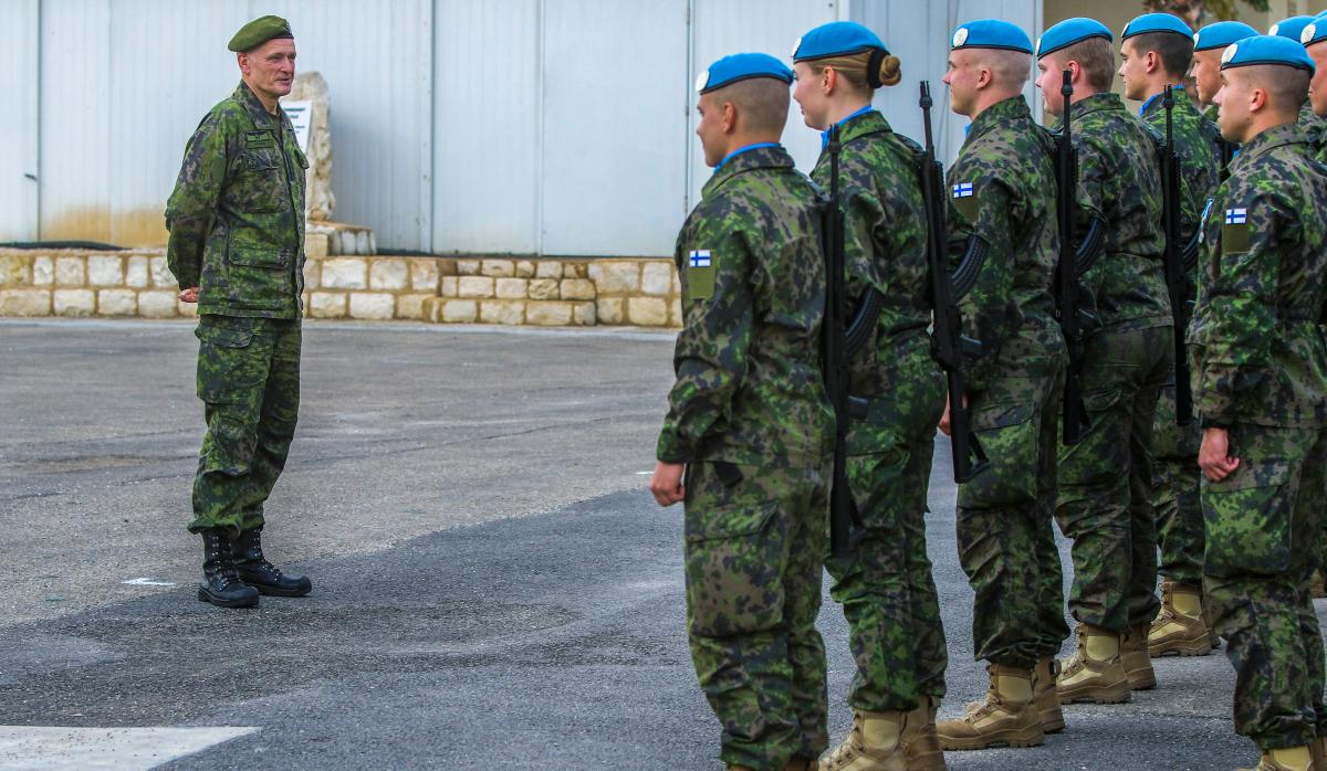 Kenraali Timo Kivinen (vasemmalla) tarkastamassa suomalaista SKJL-kriisinhallintajoukkoa. Henkilöillä on yllään vihreät maastovaatteet. Puolustusvoimain komentajan baretti on vihreä, muilla sininen.